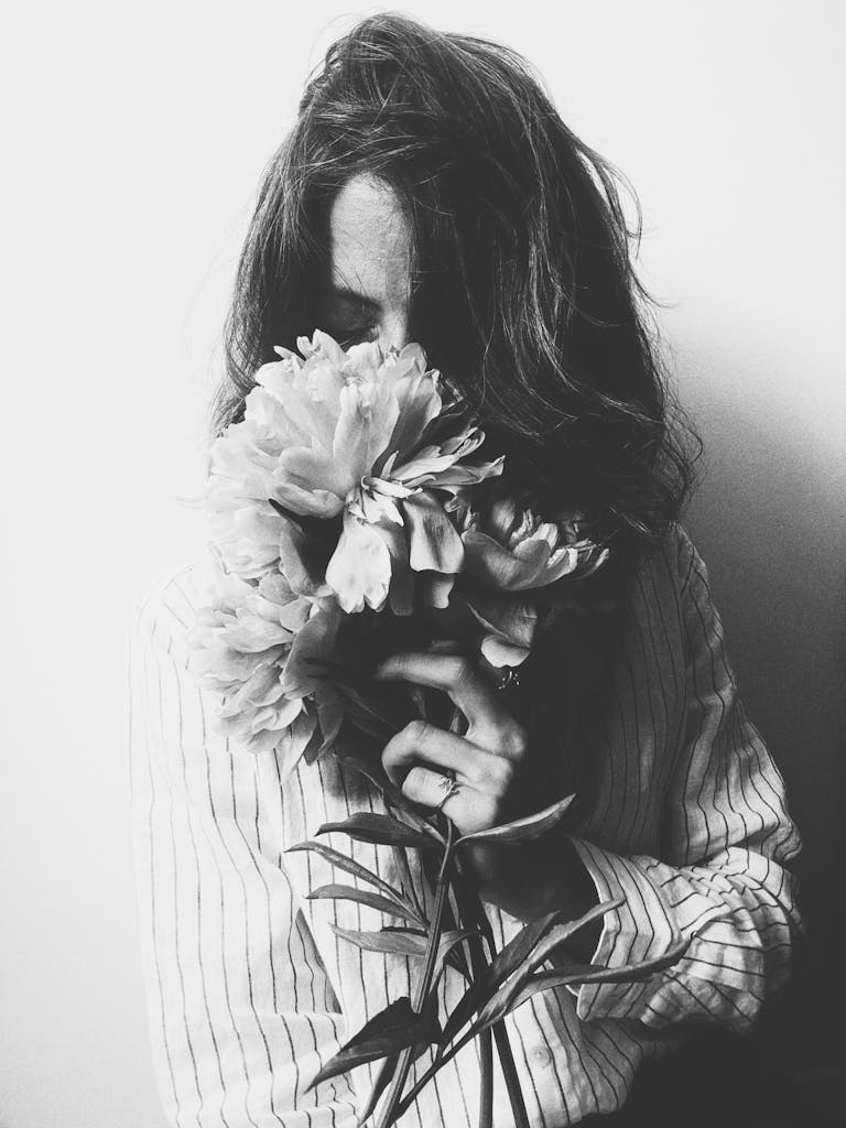 A woman in black and white holding peonies, creating a classic and artistic mood.